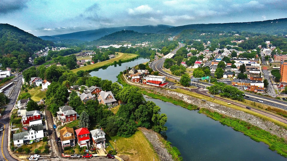 A river winding through a town with houses and a highway.