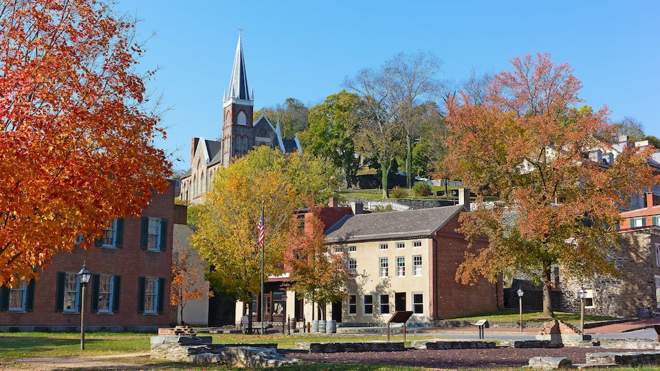 A historic town with a church, brick buildings, and autumn foliage.