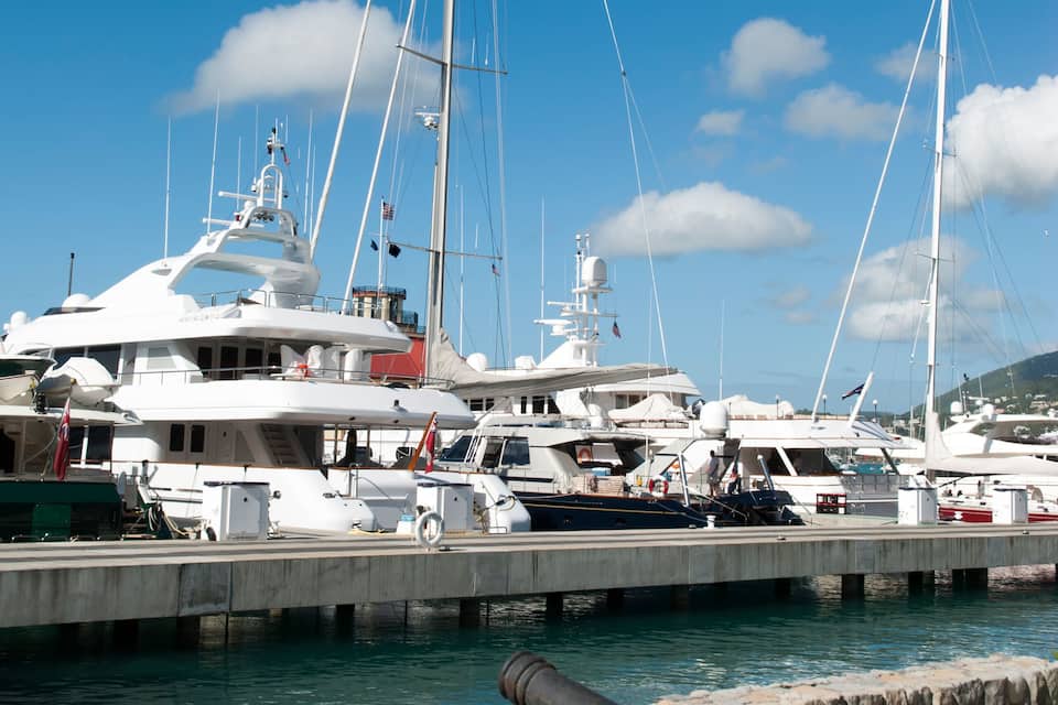 Un port de plaisance où sont amarrés plusieurs yachts, un mur de pierre et un canon.