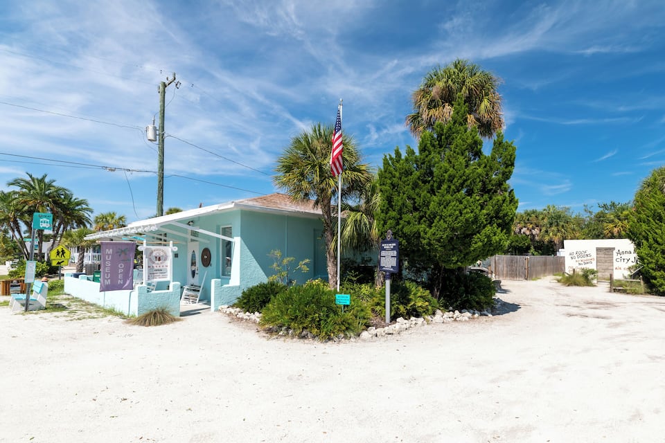 A small building with an American flag, surrounded by palm trees and a clear blue sky.