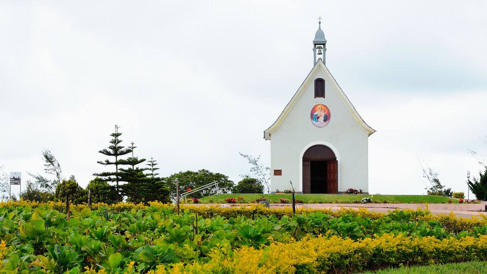 A white church with a bell tower and a colorful mural on the side.