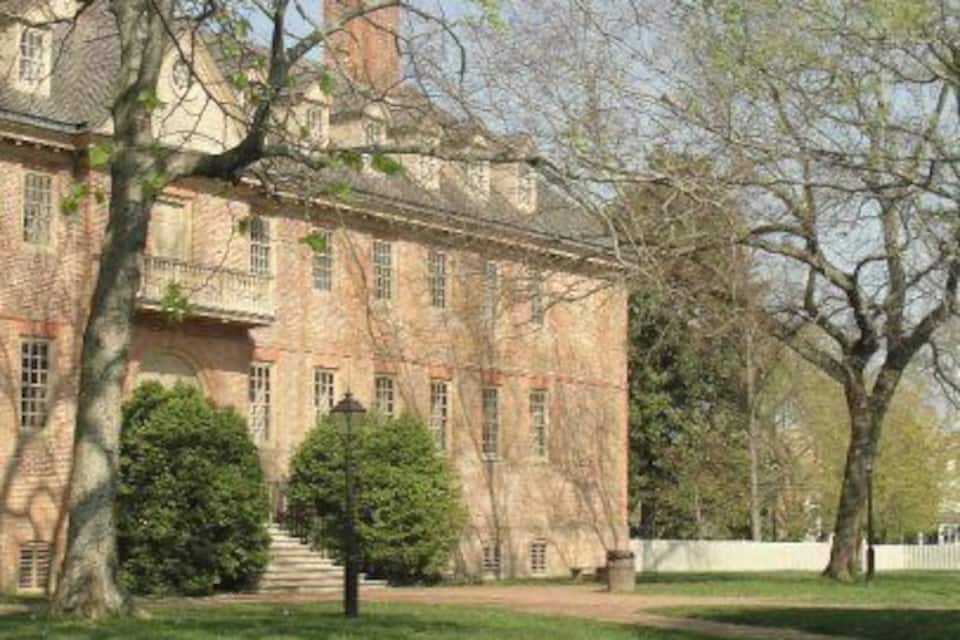 A large brick building with a central staircase and a well-maintained lawn.