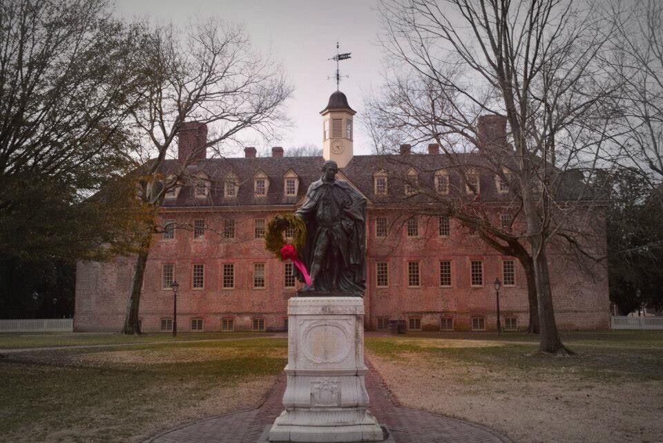 A statue in front of a large brick building with a tower.