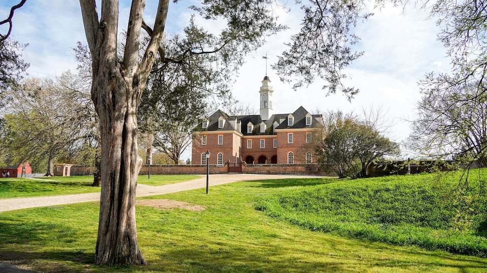 A large brick building with a tower, surrounded by green grass and trees.
