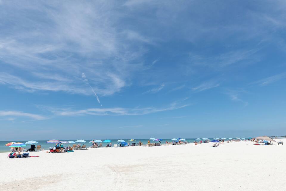 A beach with white sand and a clear blue sky.