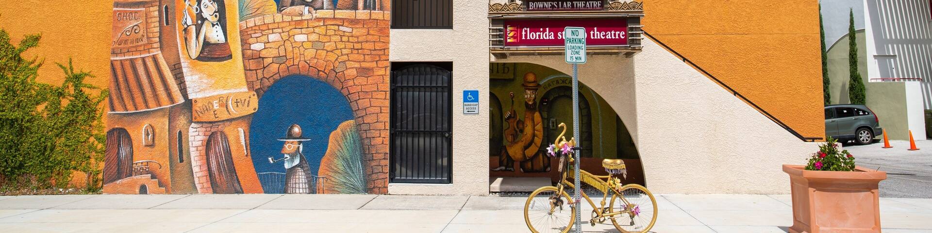 A mural on a building, a bicycle, and a sign for Florida's Theatre.