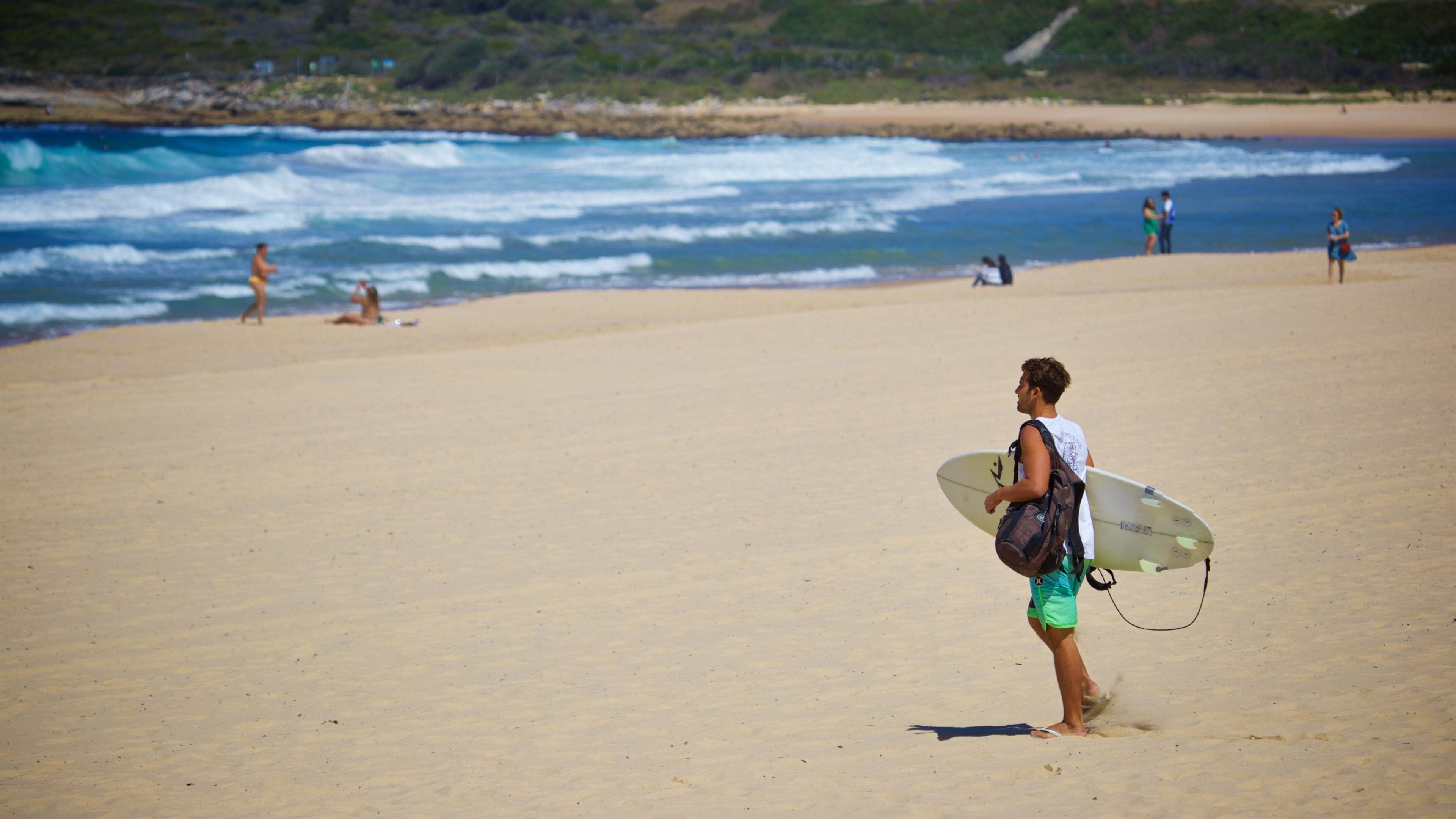 Uma praia com pessoas caminhando e sentadas.