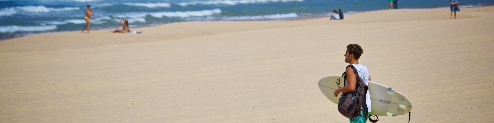 Uma praia com pessoas caminhando e sentadas.