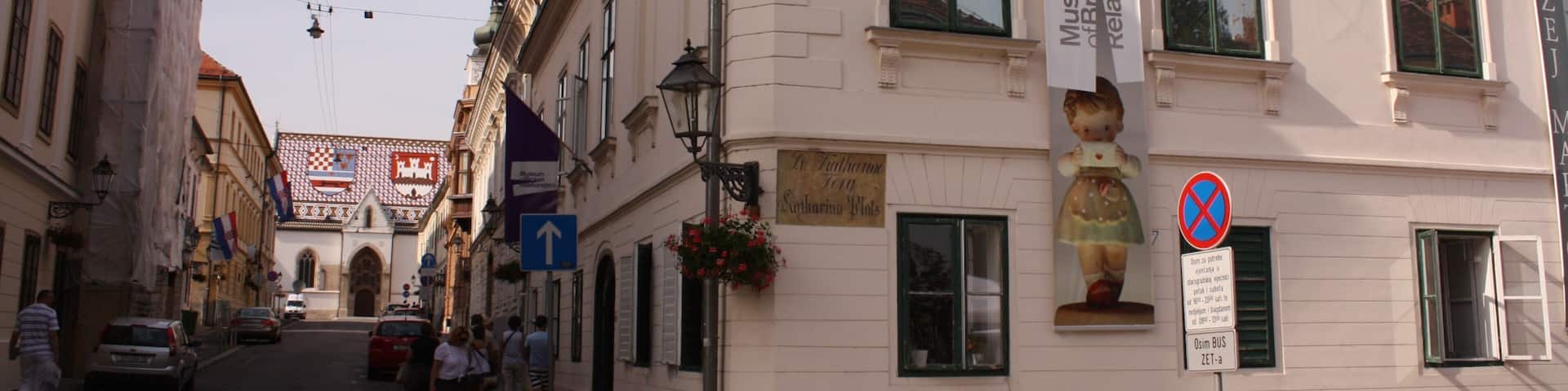 A street with buildings, a sign for Museum der Broking Relishships, and a no parking sign.