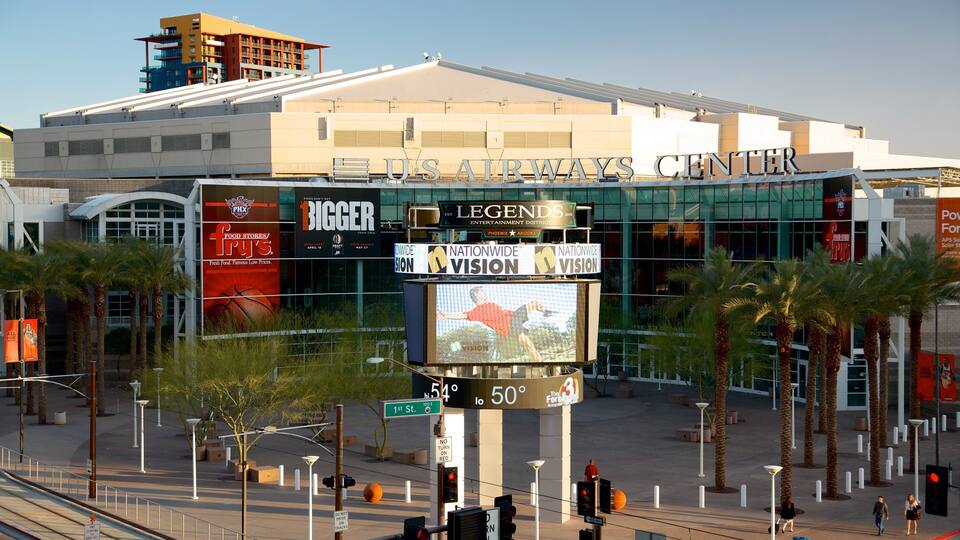 A large indoor arena with a digital scoreboard, palm trees, and various advertisements.