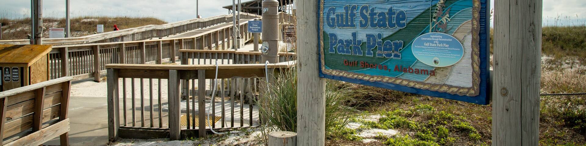 Una pasarela de madera que lleva al muelle del Parque Estatal Gulf, con un letrero.