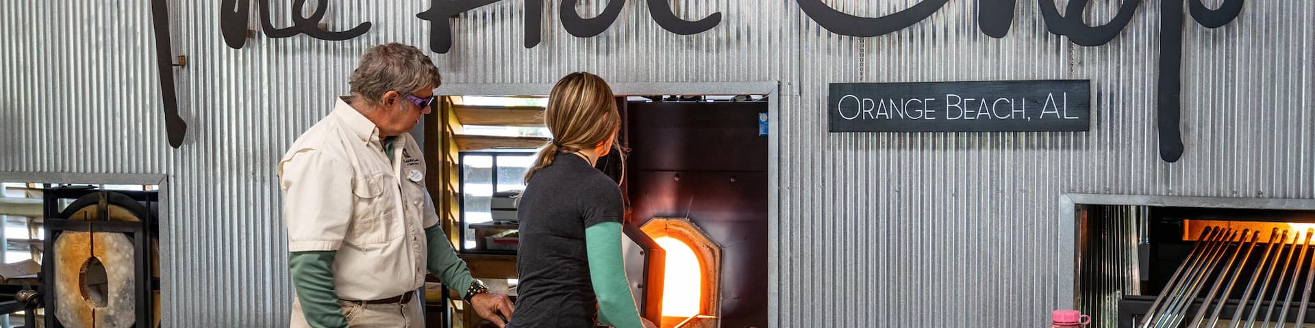 A metal wall with the words "The Hot Shop" and "Orange Beach, AL" written on it.
