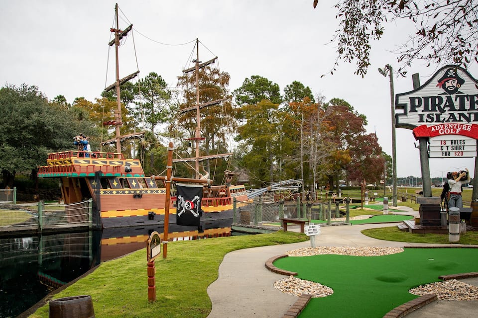 A miniature pirate ship and a sign for Pirate's Island Adventure Golf.