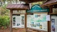 En träskylt med texten ”Bon Secour National Wildlife Refuge” och informationspaneler om olika fågelarter samt en karta.