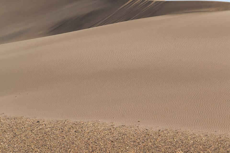 Paesaggio desertico con dune di sabbia e cielo sereno.