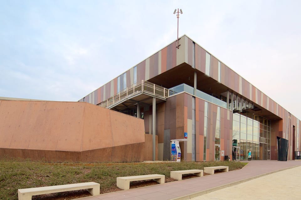 A modern building with a unique architectural design, featuring a combination of glass and metal panels, and a prominent overhang structure.