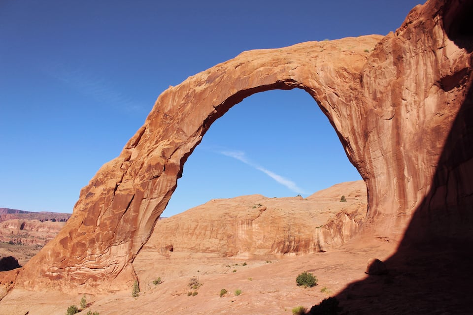 A large natural arch formation in a desert landscape.