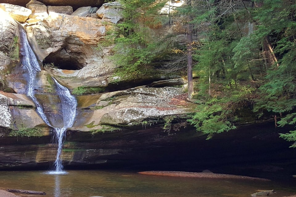 Una cascata impetuosa che si getta da una scogliera rocciosa, circondata da una fitta foresta.