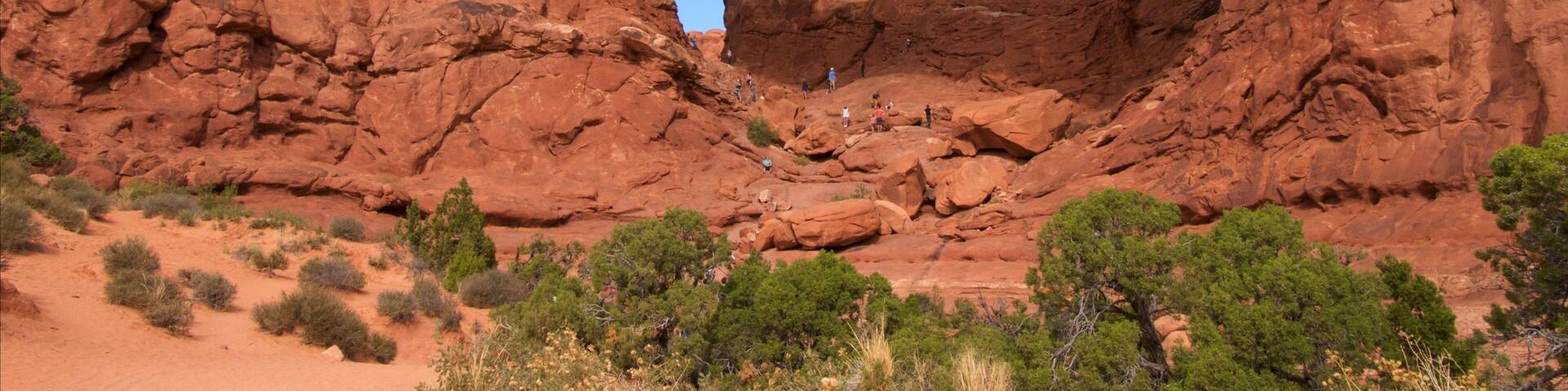A large red rock arch formation with a clear blue sky above.