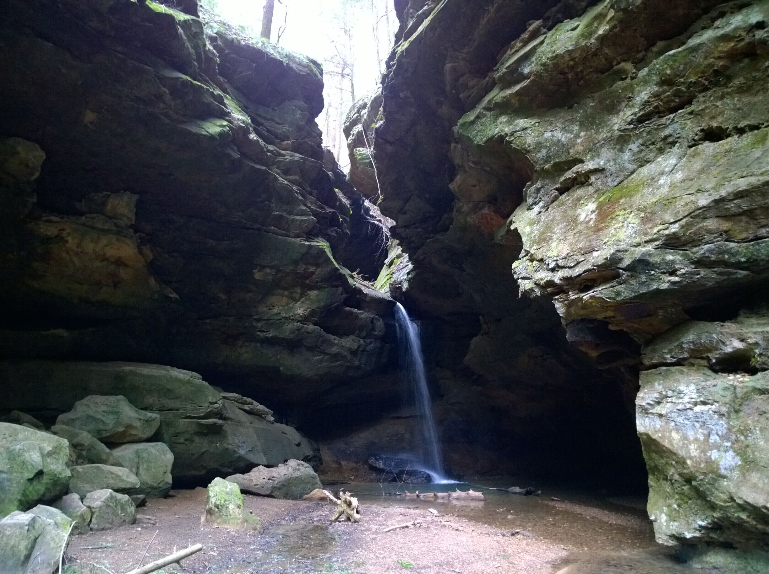 A cave with a waterfall and large rocks.