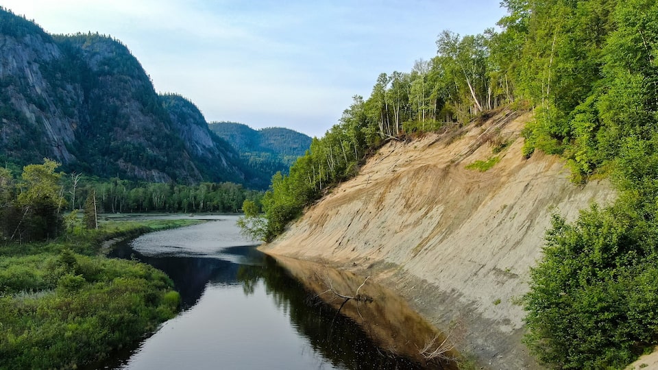 A river winding through a forested valley with steep cliffs on one side and a forested hillside on the other.