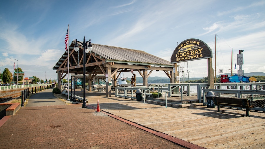 Una pasarela de madera con un cartel que dice "Welcome to Coos Bay Boardwalk" y vista al océano.