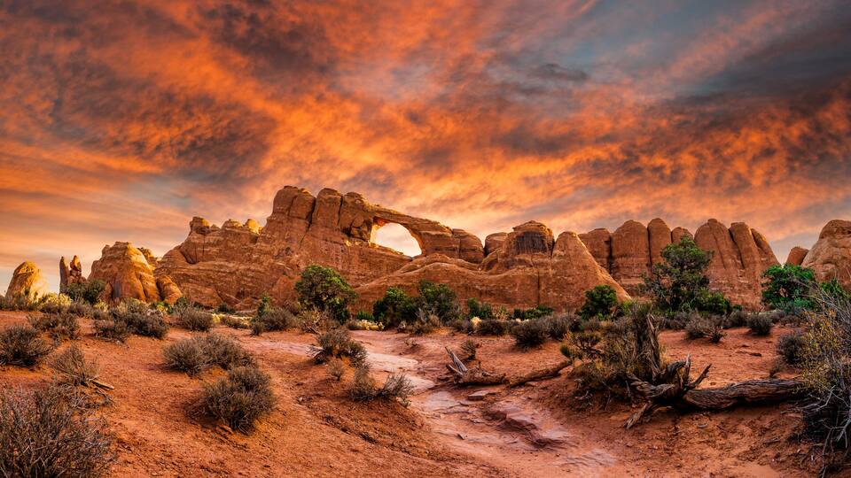 A desert landscape with prominent rock formations and a distinctive arch.
