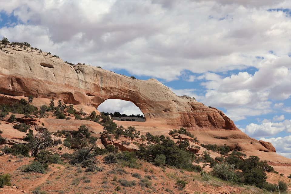 A large rock arch formation with sparse vegetation.