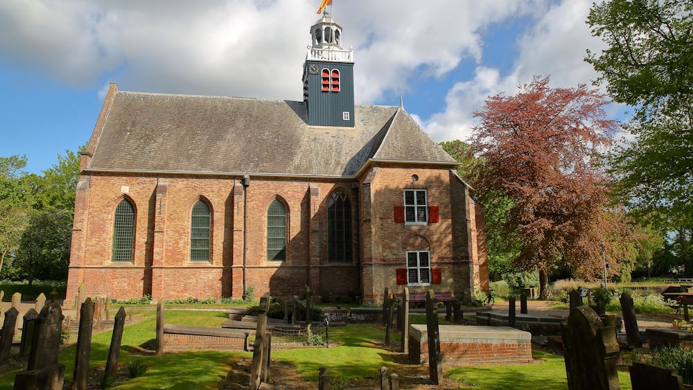 A historic church with a bell tower, brick walls, and a cemetery in front.