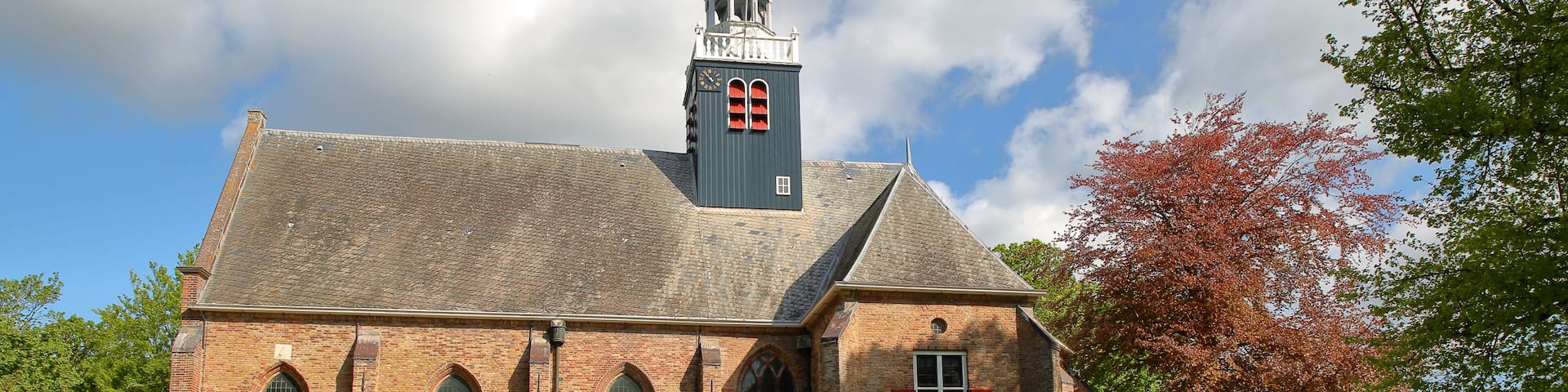 A historic church with a bell tower, brick walls, and a cemetery in front.