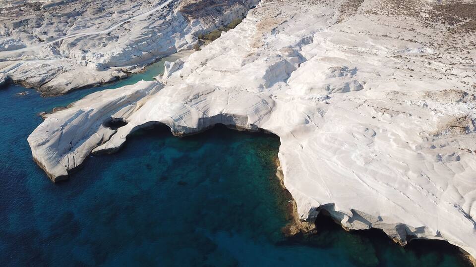 A coastal landscape with white rock formations and clear blue waters.