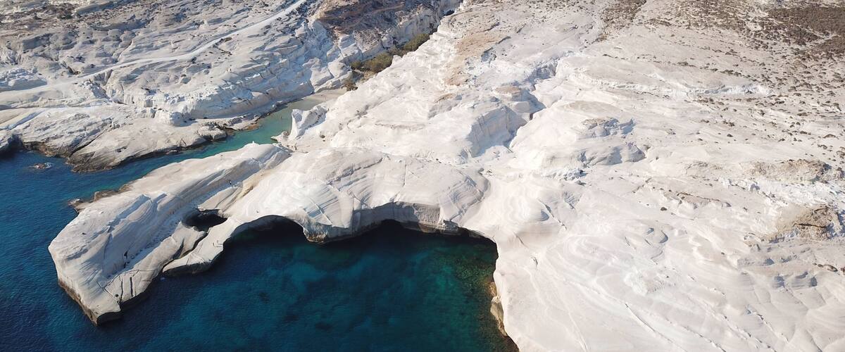 A coastal landscape with white rock formations and clear blue waters.