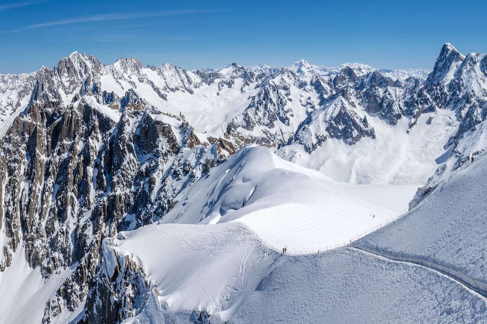 A snow-covered mountain range with sharp peaks and a clear sky.