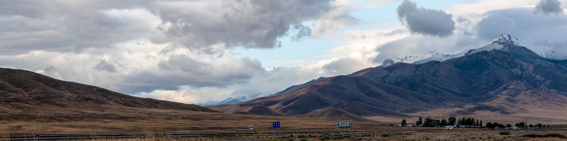 Uma autoestrada com uma paisagem montanhosa ao fundo, incluindo um pico nevado.