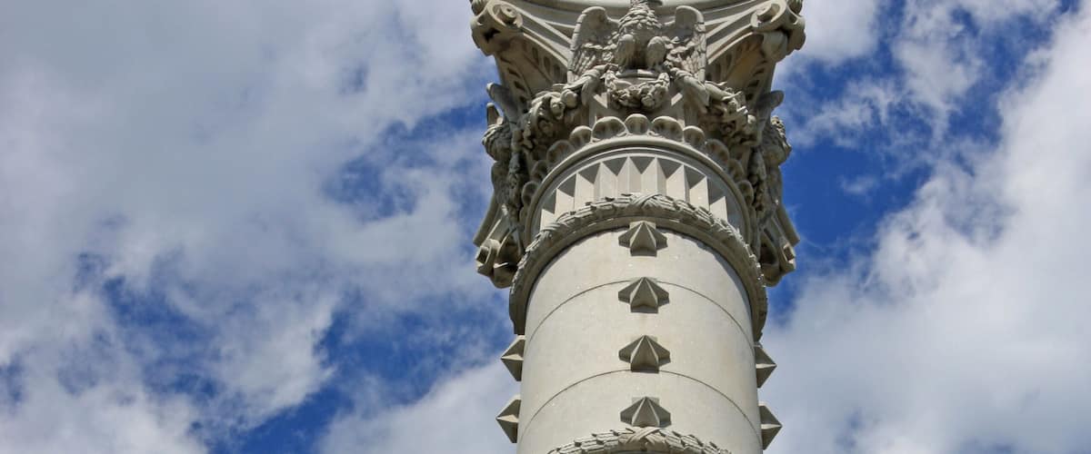 A tall monument with a statue at the top, featuring intricate carvings and the word "YORKTOWN" inscribed on the base.