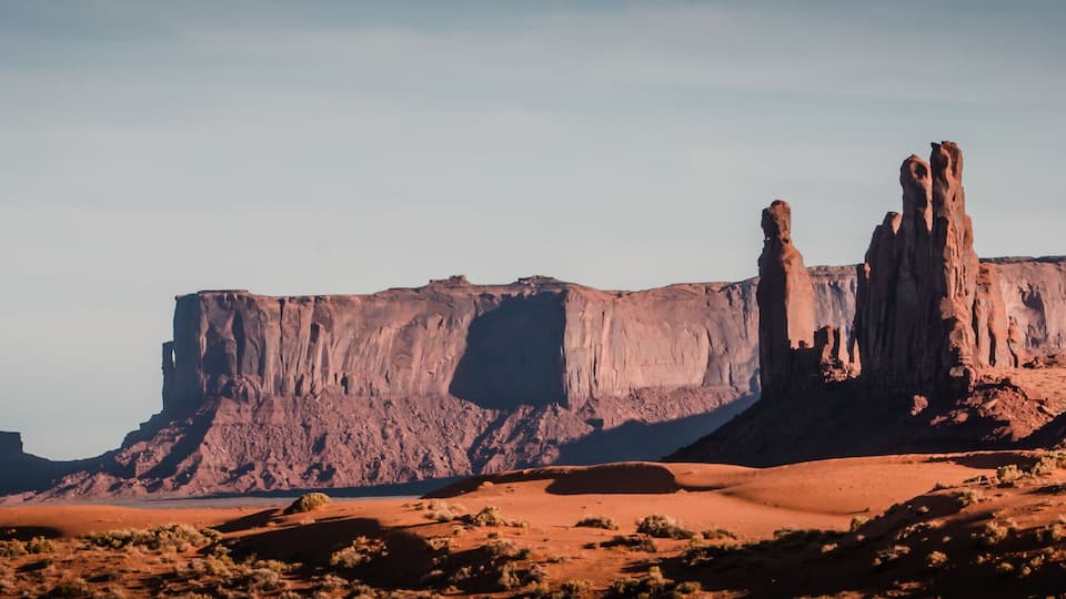A desert landscape with prominent rock formations and sparse vegetation.