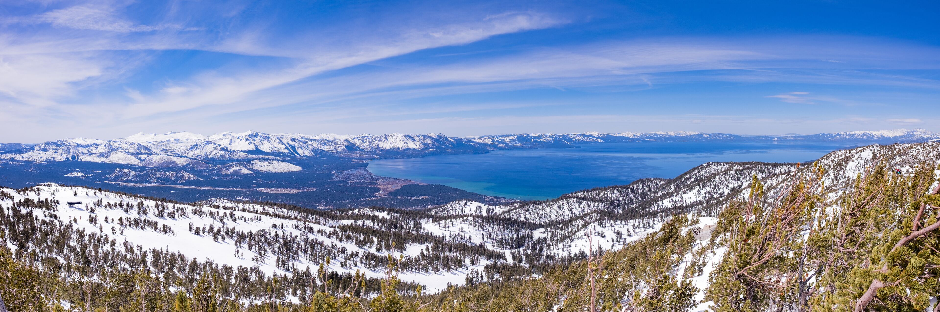 A snow-covered mountain range with a lake and distant snow-capped peaks.