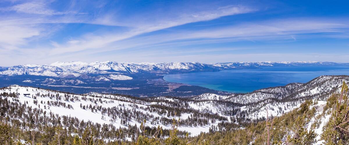 A snow-covered mountain range with a lake and distant snow-capped peaks.