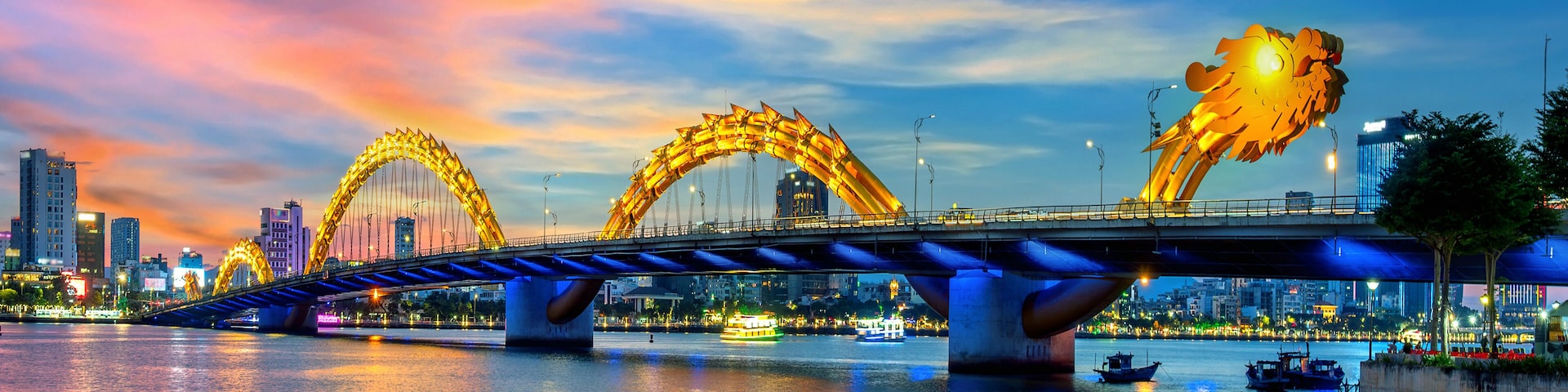 Eine Brücke mit zwei großen, beleuchteten Bögen über einem Fluss, im Hintergrund Stadtgebäude.
