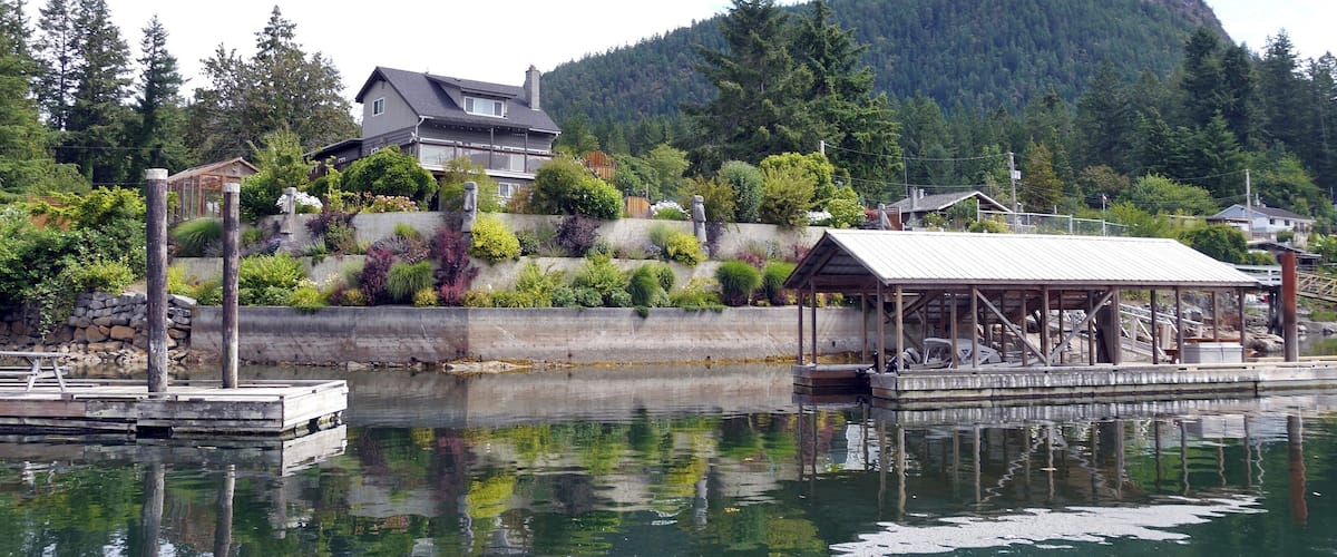A lakeside house with a dock and a mountain in the background.