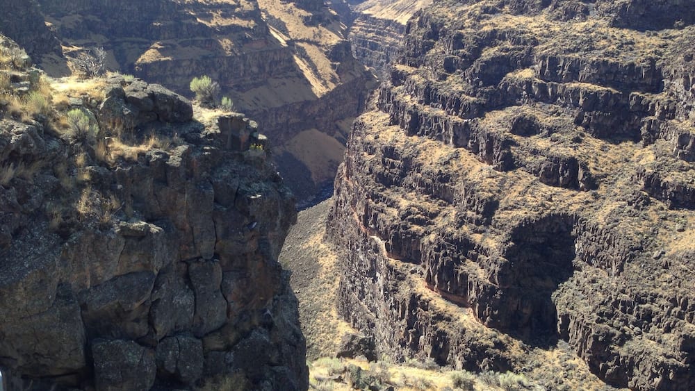 A canyon with steep rock faces and sparse vegetation.