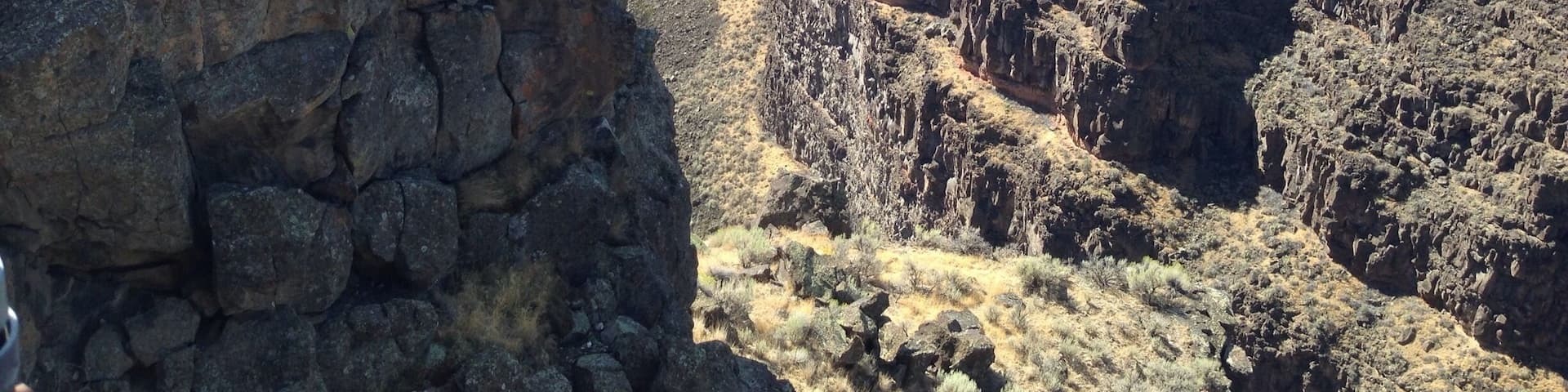 A canyon with steep rock faces and sparse vegetation.