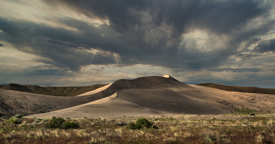 Paisagem desértica com dunas de areia e céu nublado.