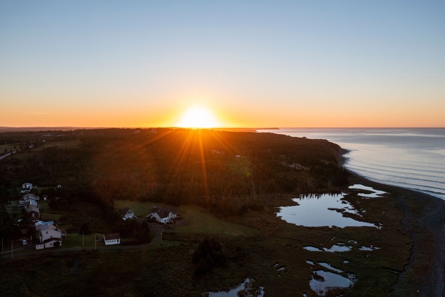 Aerial view of beautiful sunset over tranquil coastline with forest and homes, Lawrencetown, Canada.