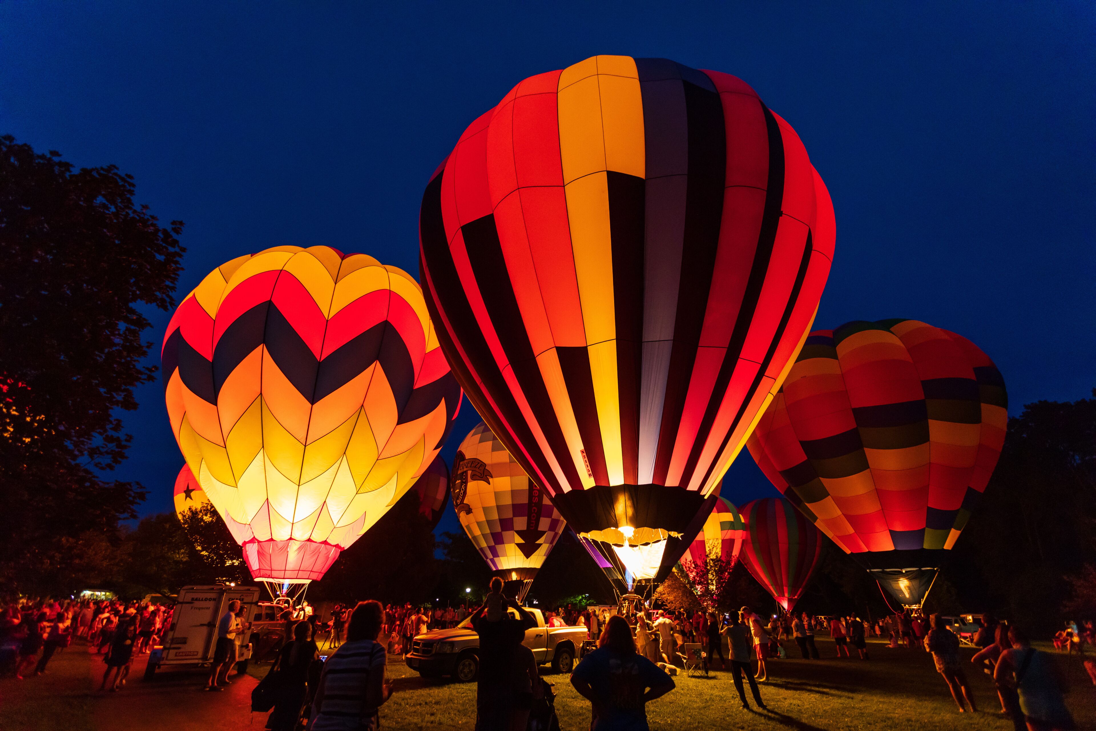 A nighttime hot air balloon festival with multiple balloons.