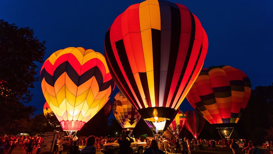 A nighttime hot air balloon festival with multiple balloons.