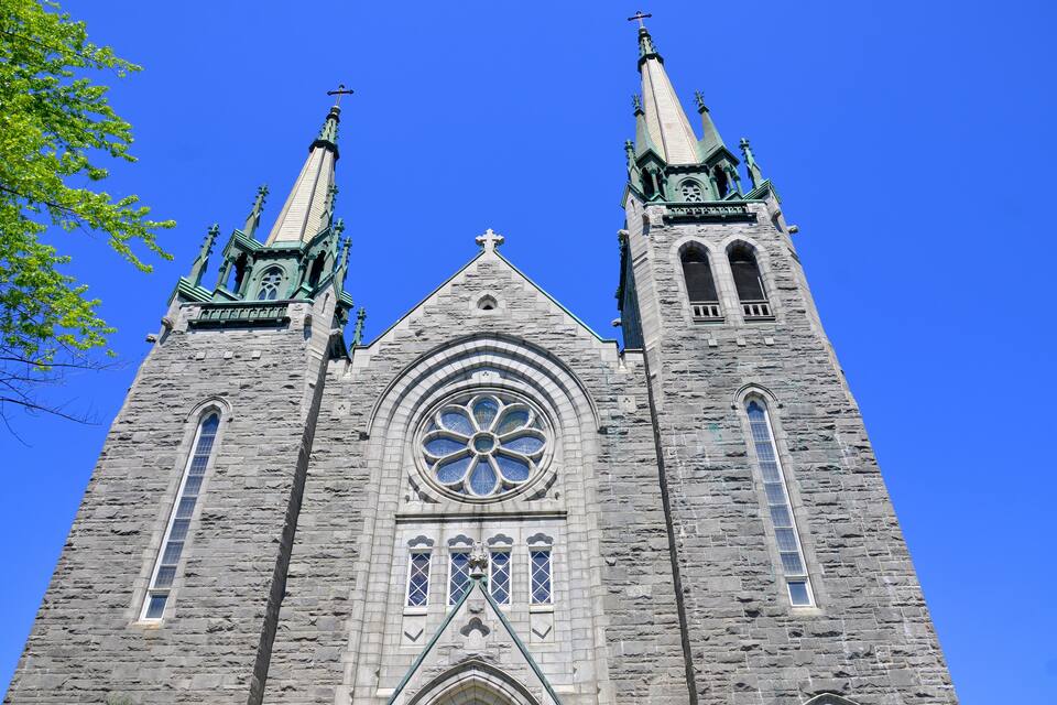 Une grande église en pierre, dotée de deux hautes flèches et d’une grande rosace.