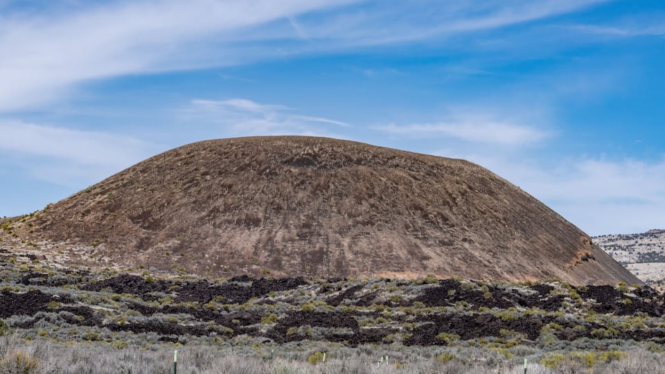A large hill with sparse vegetation in a clear sky.