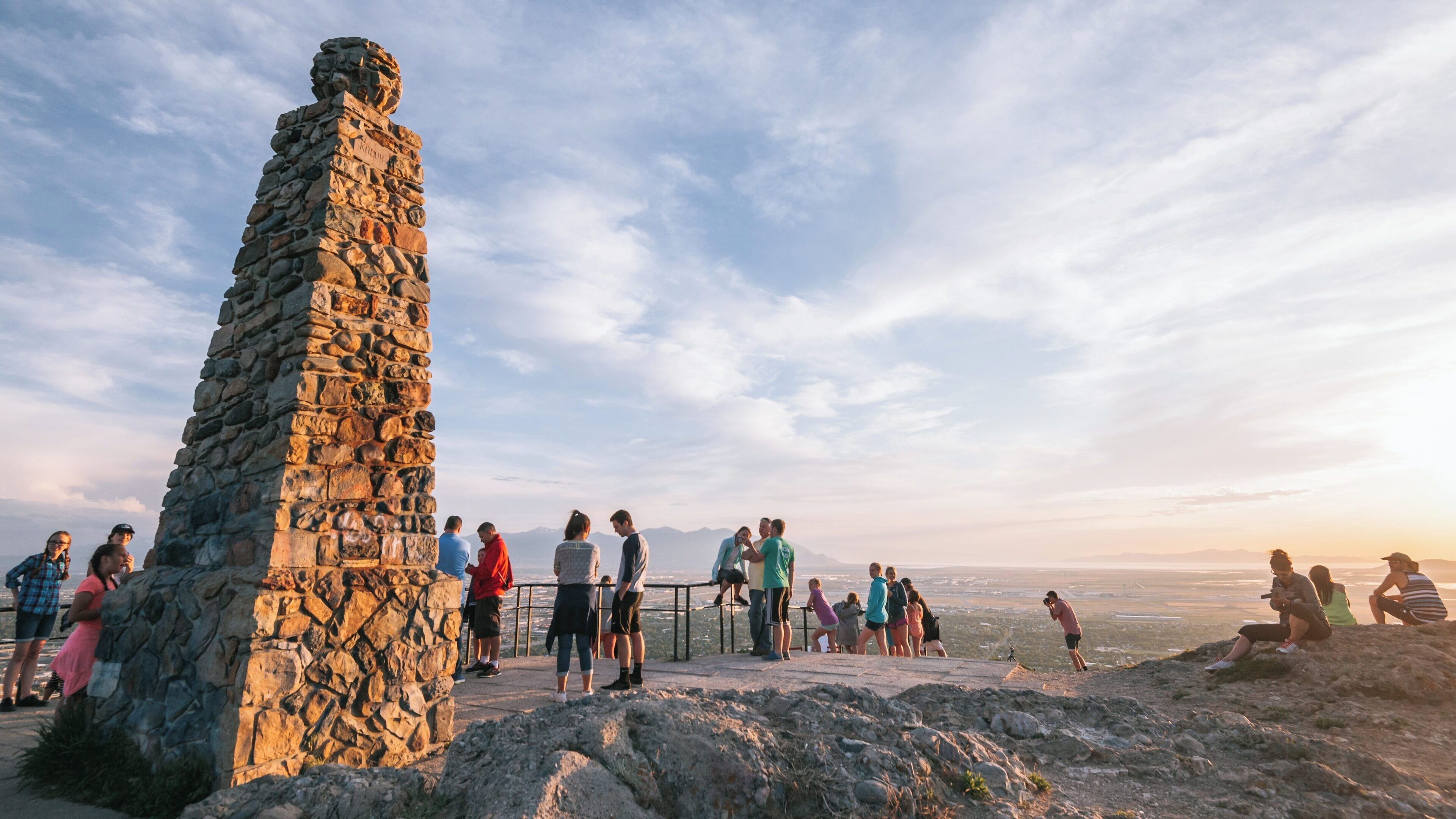 Visitors enjoy sunset views at Ensign Peak Nature Park, overlooking Salt Lake City, Utah, with scenic mountains in the distance