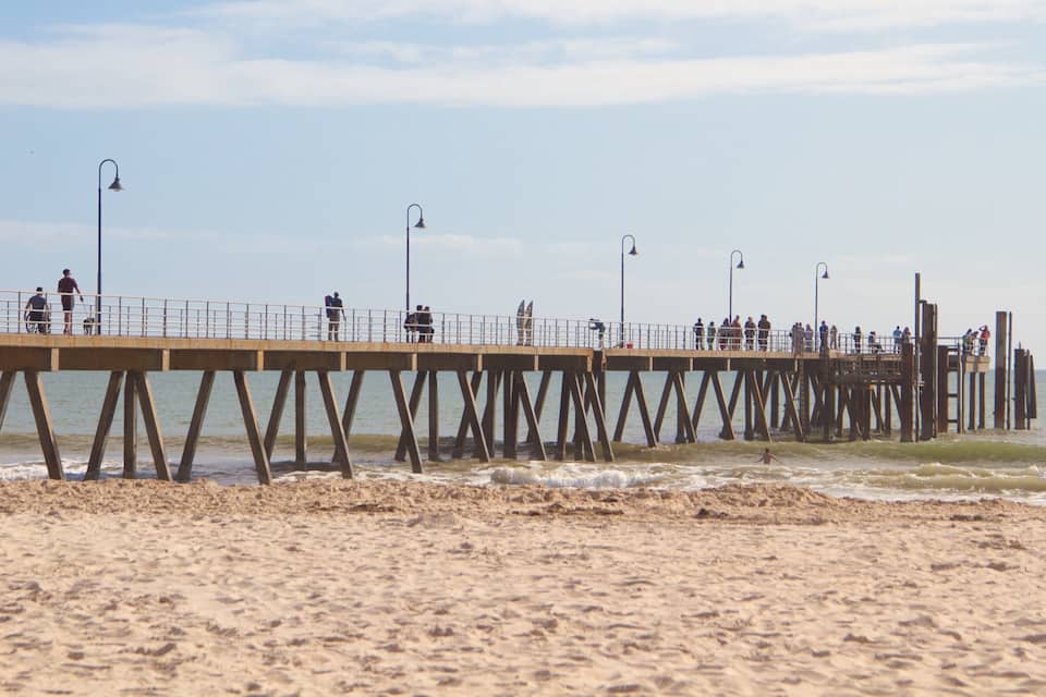 Un moll de fusta que s'endinsa a l'oceà amb gent caminant i de peu a sobre.
